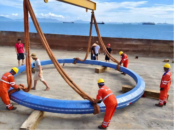 Workers lifting a large-diameter three-row roller slewing bearing at the port for export to Australia Workers lifting a large-diameter three-row roller slewing bearing at the port for export to Australia